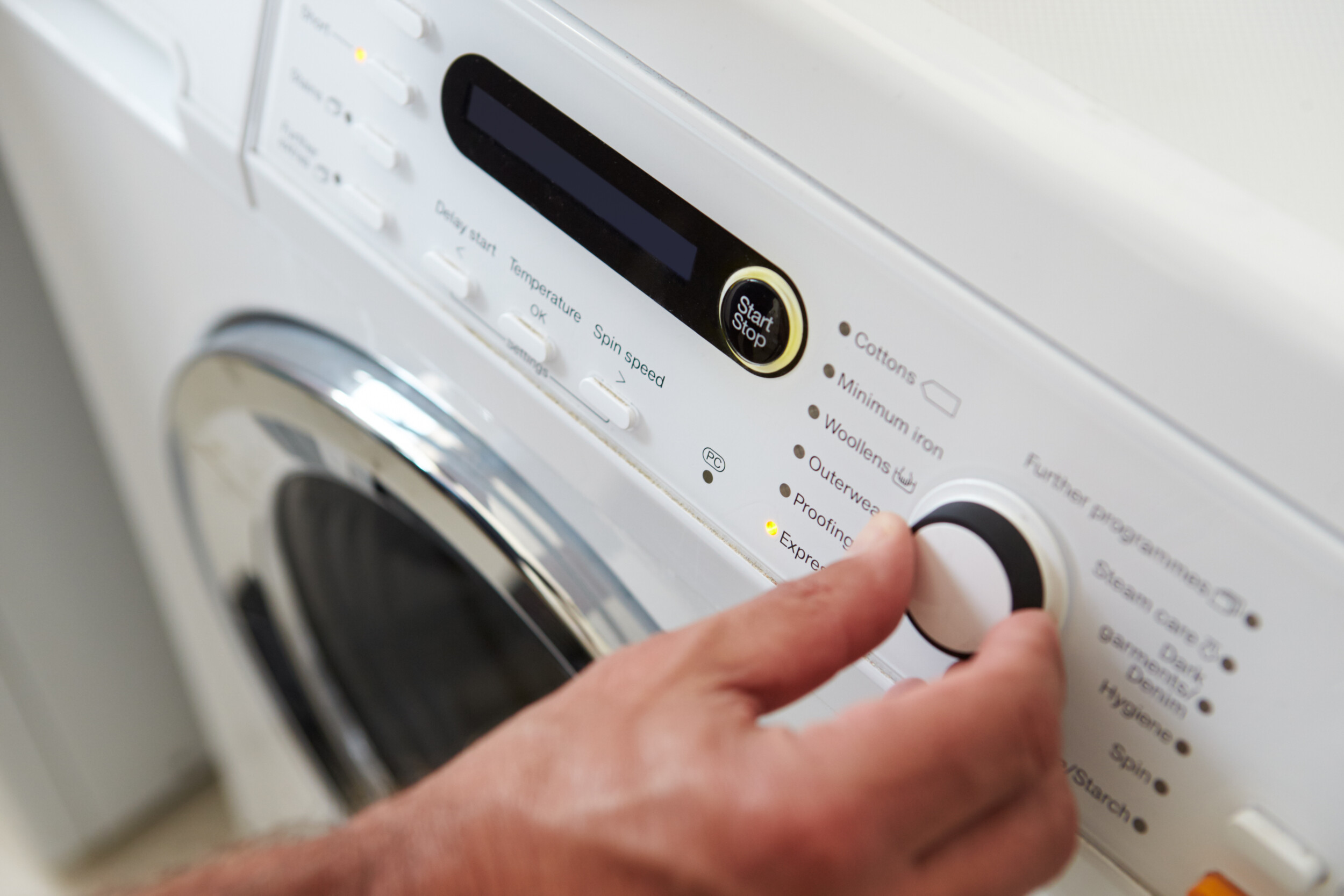 Close Up Of Man Choosing Cycle Program On Washing Machine Washing Machine Repairs in Ringwood